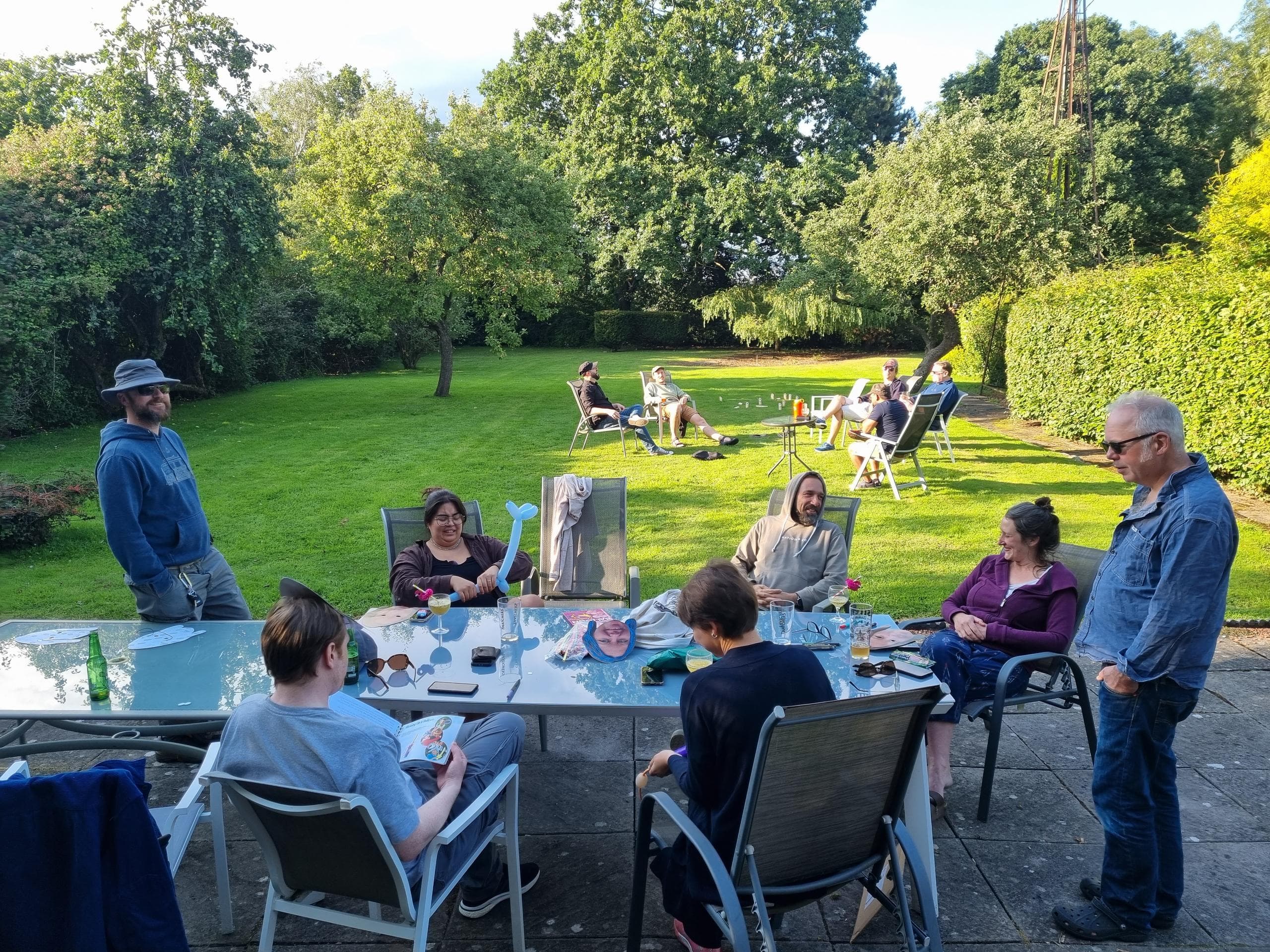 Two groups of Agile Collective staff sit in garden in the late afternoon