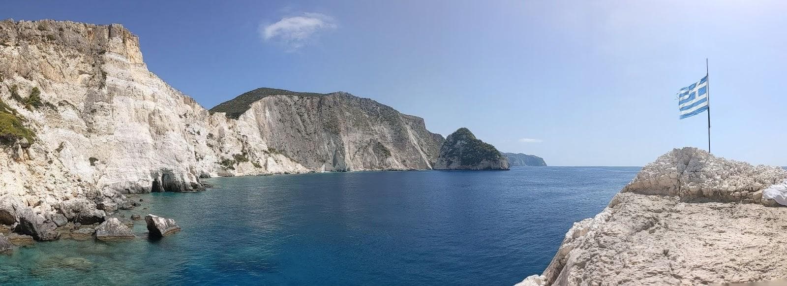 A beach in Greece with cliffs in the background on a sunny day 