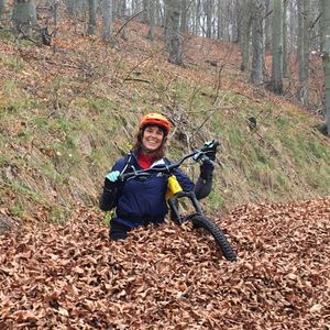 Pic of Sally wading waist deep through leaves with her bike