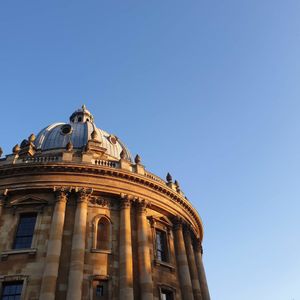 Looking up at the Radcliffe Camera building against blue sky, the builidng has an ornate facade.